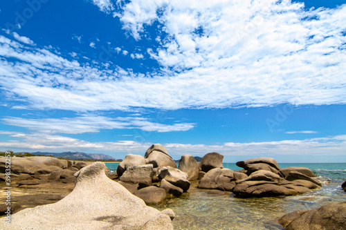 rocce e mare 01 - rocce modellate dal mare sotto un cielo azzurro con nubi bianche.