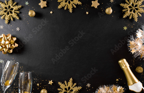 Christmas and New Year holidays background concept made from champagne, glasses, stars, snow flake with golden glitter on black wooden background. photo