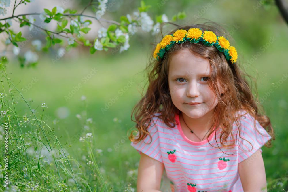 girl with wreath of dandelions on head against background of branches of cherry blossoms. girl with wreath of dandelions on head against background of branches of cherry blossoms.