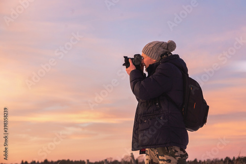 Male amateur photographer takes pictures of colorful winter sunset. Winter fairy tale with purple colors