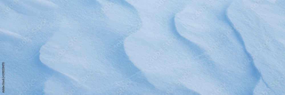Obraz premium Beautiful winter background with snowy ground. Natural snow texture. Wind sculpted patterns on snow surface. Wide panoramic texture for background and design.
