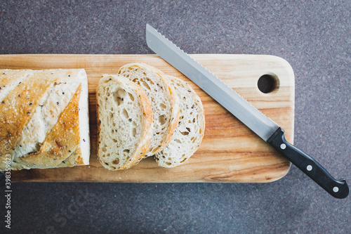 simple food ingredients, sourdough bread with mixed seeds sliced up on cutting board next to bread knife photo