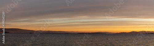 banner panorama of sunset over a calm ocean with hills and mountains in the background