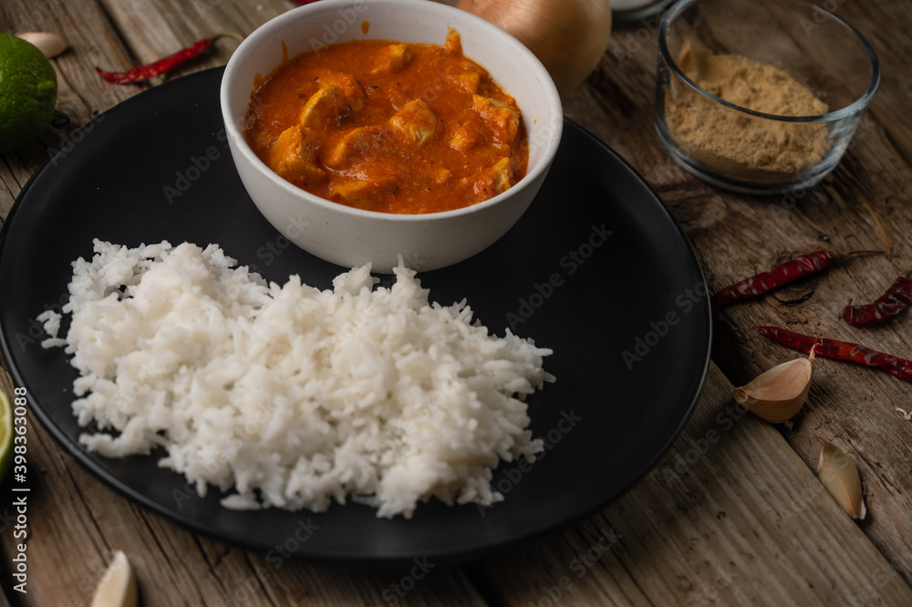 Close-up view of delicious chicken tikka masala curry and rice on rustic wooden table with spices background. Traditional Indian dish. Exotic tasty meal. Appetizing photo for menu or recipe Close-up view of delicious chicken tikka masala curry and rice on rustic wooden table with spices background. Traditional Indian dish. Exotic tasty meal. Appetizing photo for menu or recipe