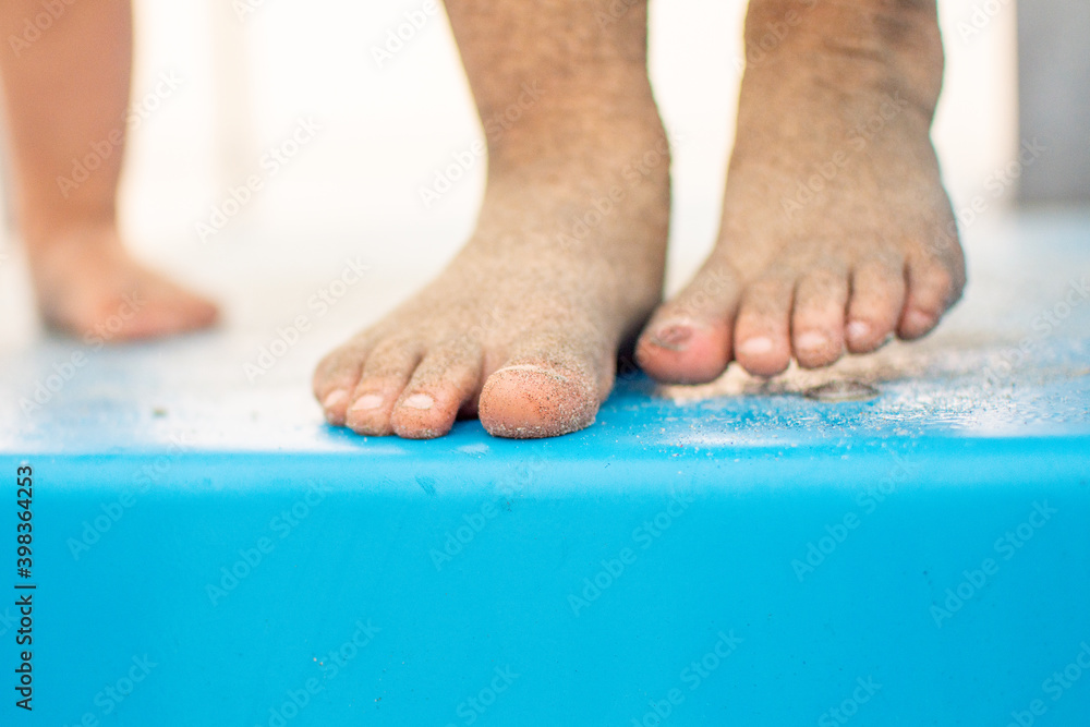 Closeup of Small child's feet covered in beach sand standing on an aqua blue lifeguard tower with a blurry background and selective focus Closeup of Small child's feet covered in beach sand standing on an aqua blue lifeguard tower with a blurry background and selective focus