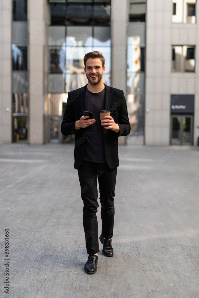 Confident young businessman using cell phone and drinking coffee in the city Confident young businessman using cell phone and drinking coffee in the city