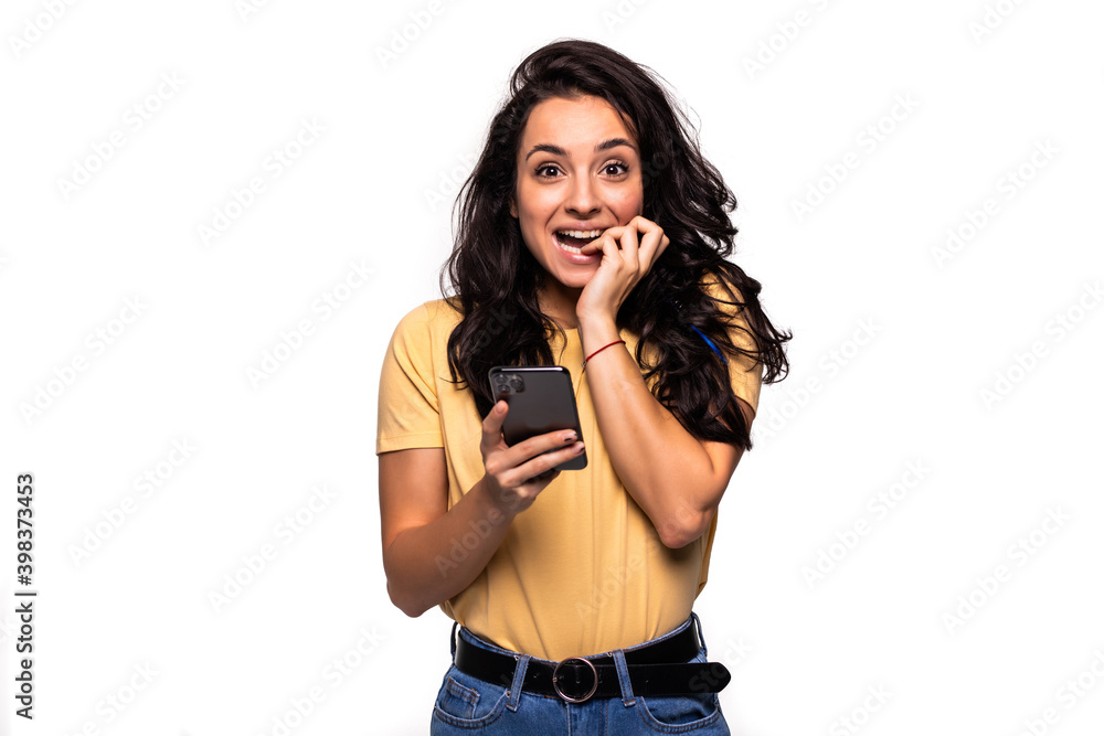 Fototapeta premium Portrait of a shocked woman using mobile phone isolated over white background