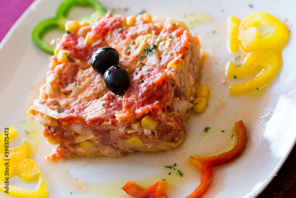 Mixed tomatoes and canned tuna - Timbale dish-served with pepper on a plate