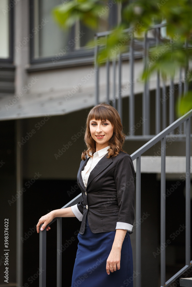 Young woman weared in classic business suit on background of a City park. Business style girl in Summer City on background of new park near a building. Street style Modern strict urban girl. Young woman weared in classic business suit on background of a City park. Business style girl in Summer City on background of new park near a building. Street style Modern strict urban girl.