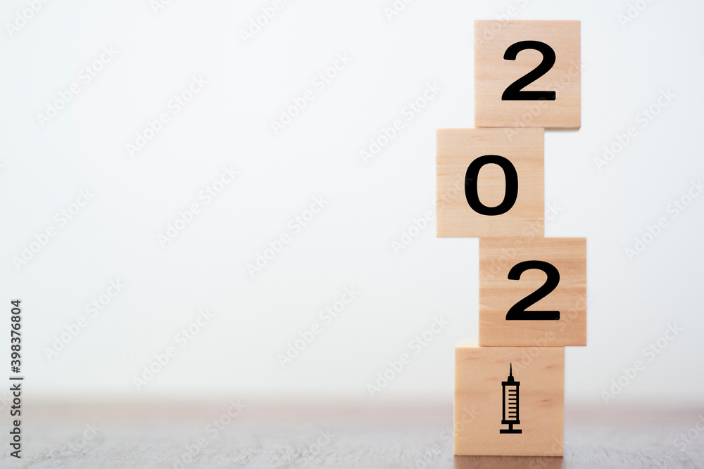 New year 2021 on wooden cubes with vaccine syringe. Concept of Covid-19 vaccination New year 2021 on wooden cubes with vaccine syringe. Concept of Covid-19 vaccination
