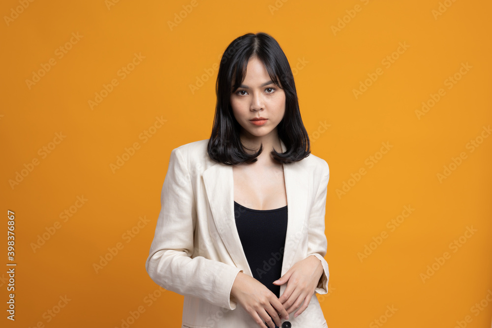 Attractive Beautiful asian woman standing and posing. Sexy female in suit on isolated yellow background. Attractive Beautiful asian woman standing and posing. Sexy female in suit on isolated yellow background.