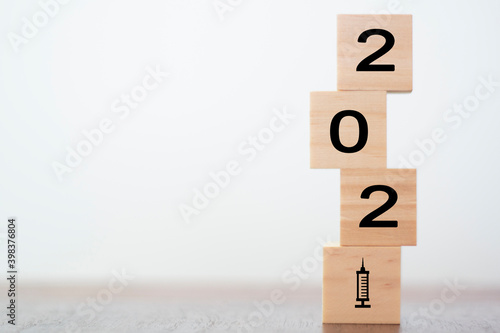 New year 2021 on wooden cubes with vaccine syringe. Concept of Covid-19 vaccination