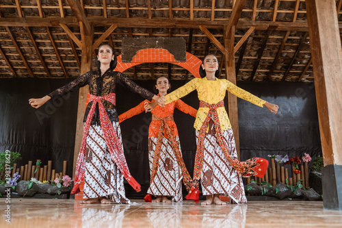 portrait of three young women presenting traditional Javanese dance movements in traditional javanese joglo house