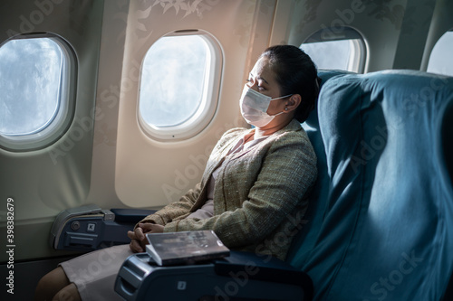 Asian businesswoman wearing face mask, looking outside the window.