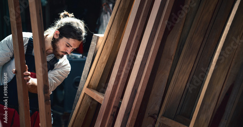 carpenter in wood workshop selecting wooden frame for his workwood