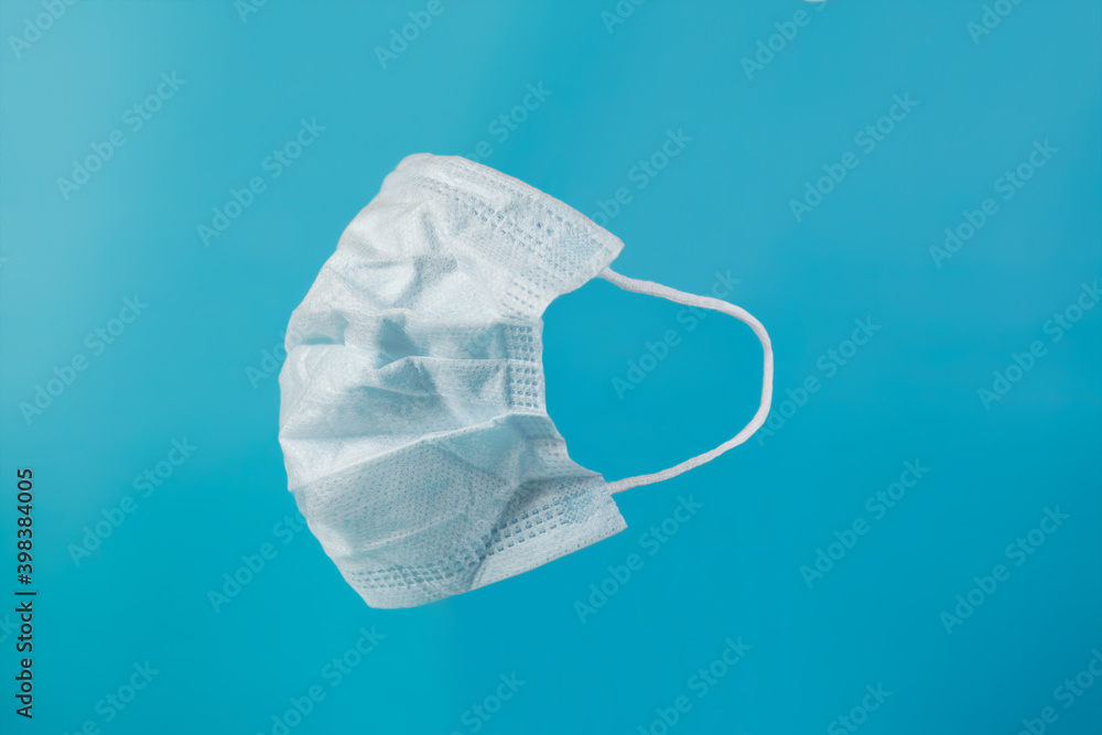Medical white mask. Antivirus mask. White face mask during a pandemic virus COVID-19. Face protective mask on a blue background. Space for text Medical white mask. Antivirus mask. White face mask during a pandemic virus COVID-19. Face protective mask on a blue background. Space for text