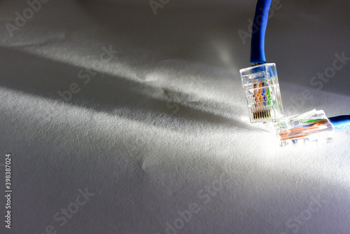 Ethernet patch cable end connector plug macro, closeup. Rj 45, 8p8c, with light flare overexpose, simple internet connection hardware, data transfer abstract concept. White background, individual wire