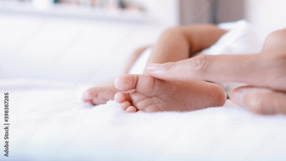Close up of little feet baby newborn on comfortable bed,Mom hands touching take care and love Close up of little feet baby newborn on comfortable bed,Mom hands touching take care and love