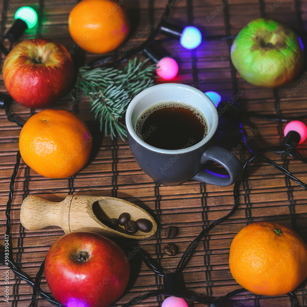 cup of coffee, apples, tangerines and garland on a dark background cup of coffee, apples, tangerines and garland on a dark background