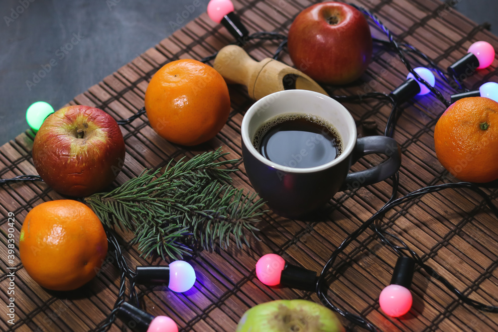 cup of coffee, apples, tangerines and garland on a dark background cup of coffee, apples, tangerines and garland on a dark background