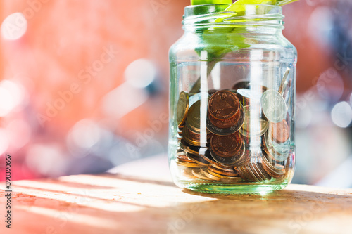 Closeup coins in a glass of bottle on sunlight using as financial and money savings concept