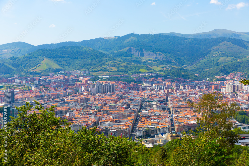 Scenic panoramic view of modern Bilbao cityscape surrounded by mountain ranges in summer, Spain ..