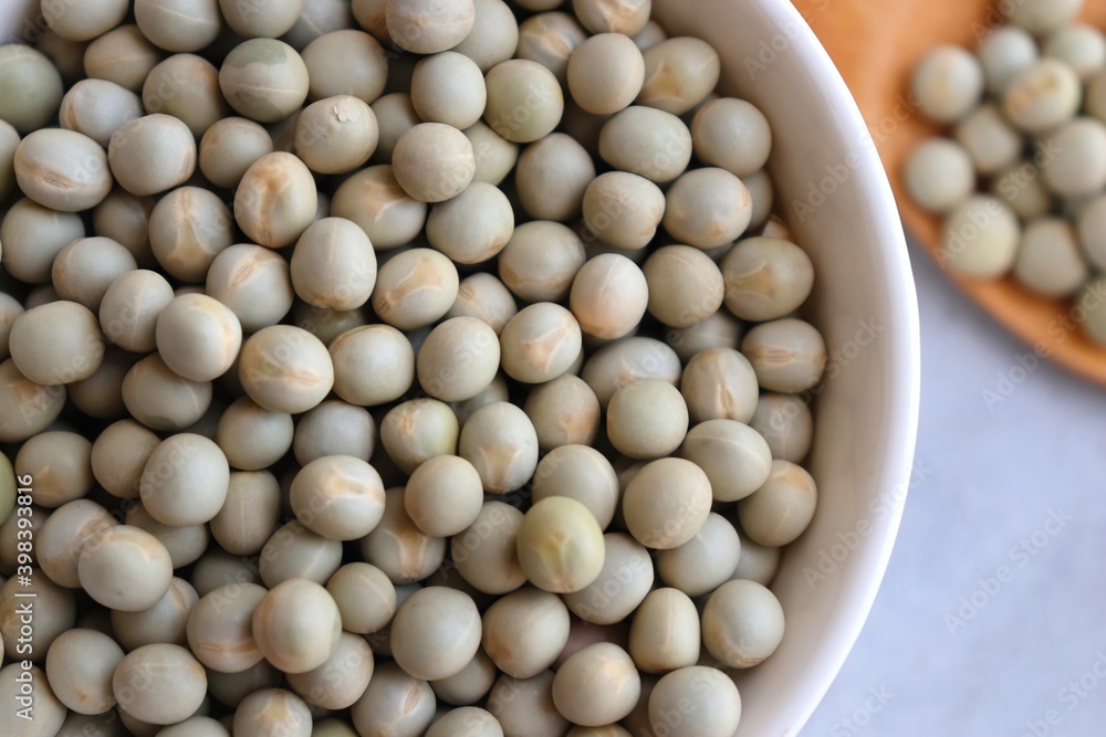 Uncooked dried green peas, also known as vatane in Marathi. in a ceramic bowl on white background. Preparation for making Peas curry or vatana curry. copy space. Uncooked dried green peas, also known as vatane in Marathi. in a ceramic bowl on white background. Preparation for making Peas curry or vatana curry. copy space.