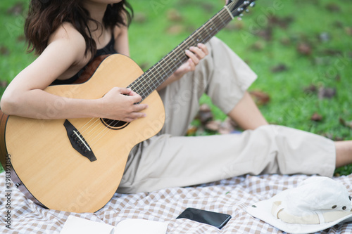 Beautiful Asian student picnic in the park and thinking Composing song photo