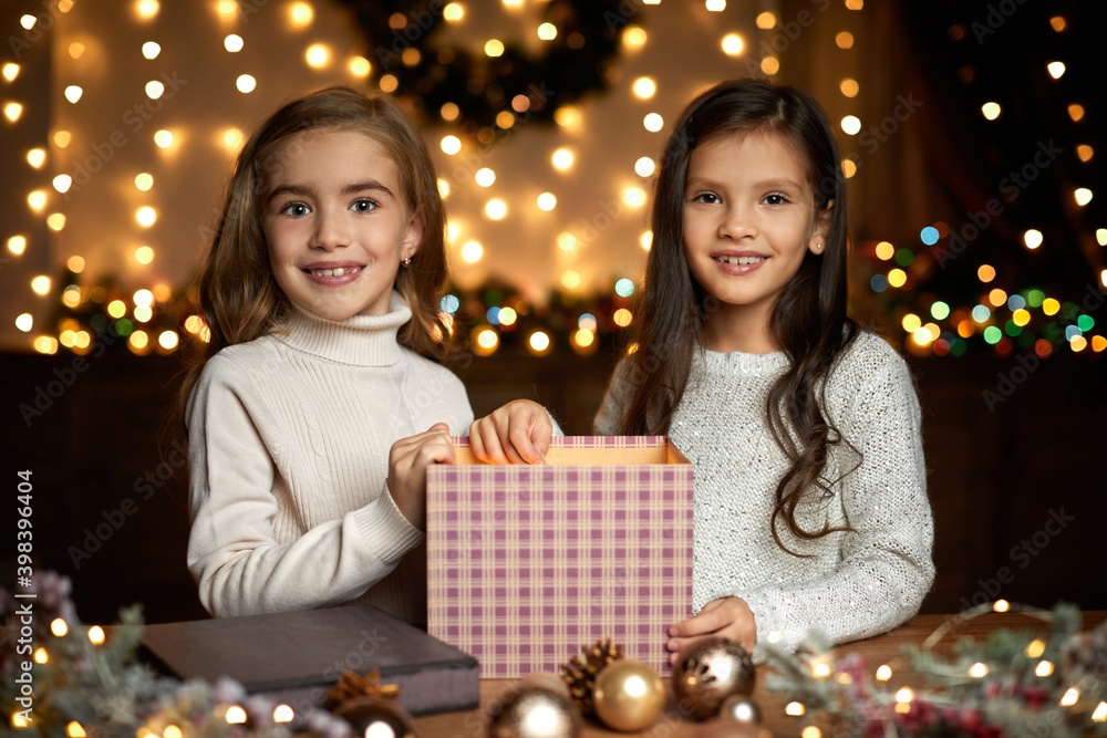 two beautiful happy little child girls opening magic Christmas gift box at home. Christmas miracle