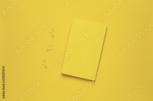 Yellow notebook and paperclip light bulb idea on yellow background, Color of the year 2021. Illuminating