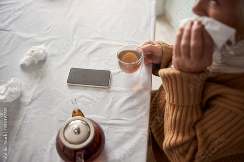 Old woman sitting at the table with cup of tea