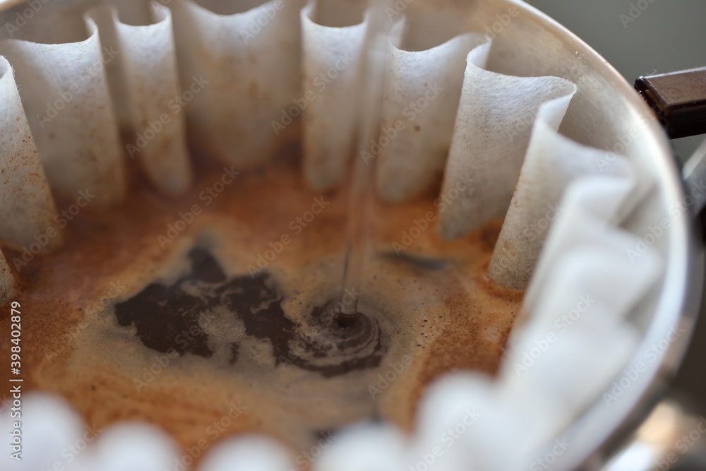 Barista making coffee with a pour over coffee maker in a dripper and