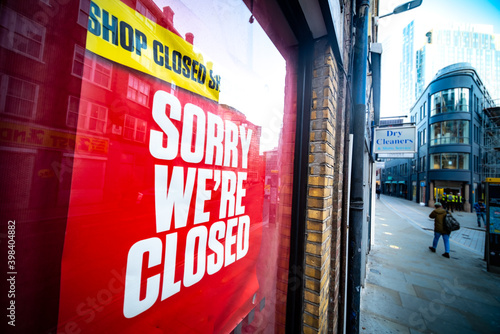 'Sorry We're Closed' sign in high street shop window- many shops are now closed due to the Covid 19 pandemic