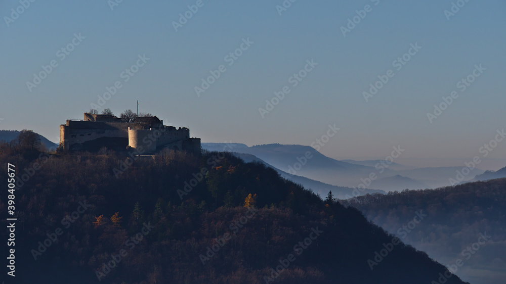 Beautiful view of historic castle ruin Hohenneuffen on the foothills of Swabian Alb, Germany in the morning sun in late autumn with foggy air in the surrounding valleys.