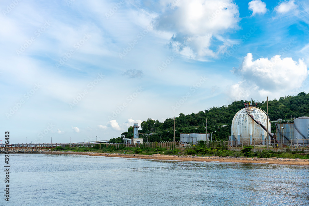 Naklejka premium Natural gas or fuel storage tank behind a hill on the coast on a clear day with blue sky
