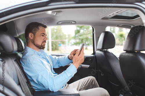 Handsome man with mobile phone in modern car © Pixel-Shot