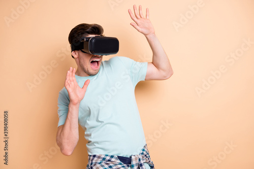 Portrait of nice terrified guy wearing vr helmet feeling fear exploring cyber space isolated over beige pastel color background