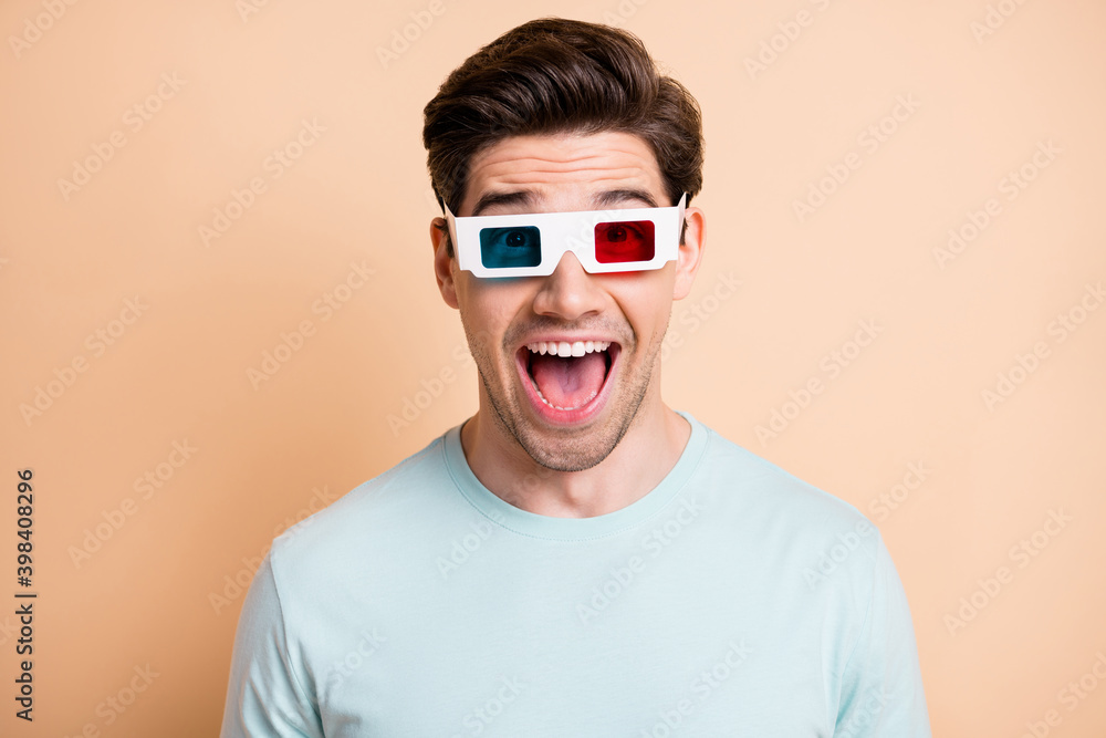 Close-up portrait of nice cheerful amazed guy watching film wearing 3d specs having fun isolated over beige pastel color background Close-up portrait of nice cheerful amazed guy watching film wearing 3d specs having fun isolated over beige pastel color background