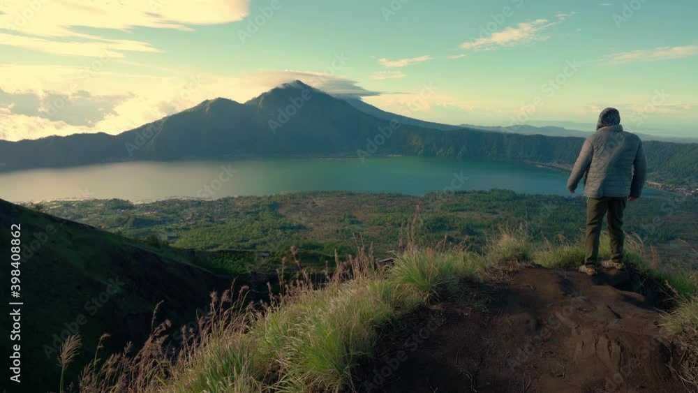 Traveler man looking on Mount Batur Bali from the top active Volcano after Mount Batur Sunrise Trekking - one of the most popular tourist destination in Bali, Indonesia. 4K Traveler man looking on Mount Batur Bali from the top active Volcano after Mount Batur Sunrise Trekking - one of the most popular tourist destination in Bali, Indonesia. 4K