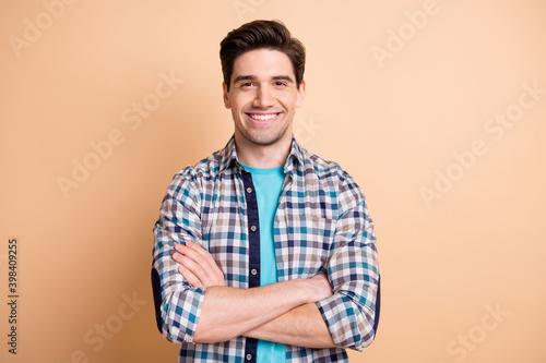 Portrait of nice cheerful content guy it expert wearing checked shirt folded arms isolated over beige pastel color background