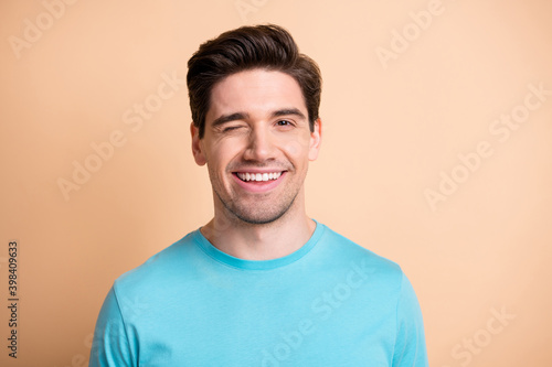 Close-up portrait of nice attractive flirty cheerful well-groomed guy winking isolated over beige pastel color background