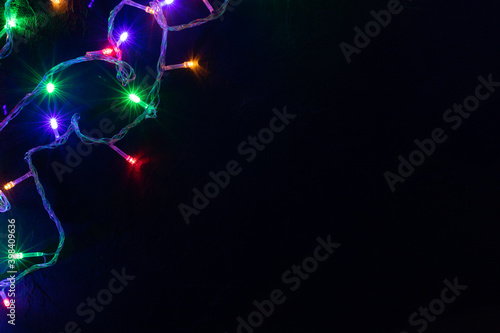 Christmas banner background. Glowing Christmas tree garland on dark background. Copy space. Festive background. © Anna