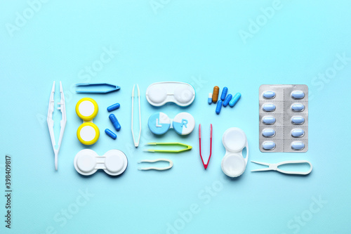 Containers with contact lenses, tweezers and pills on color background photo