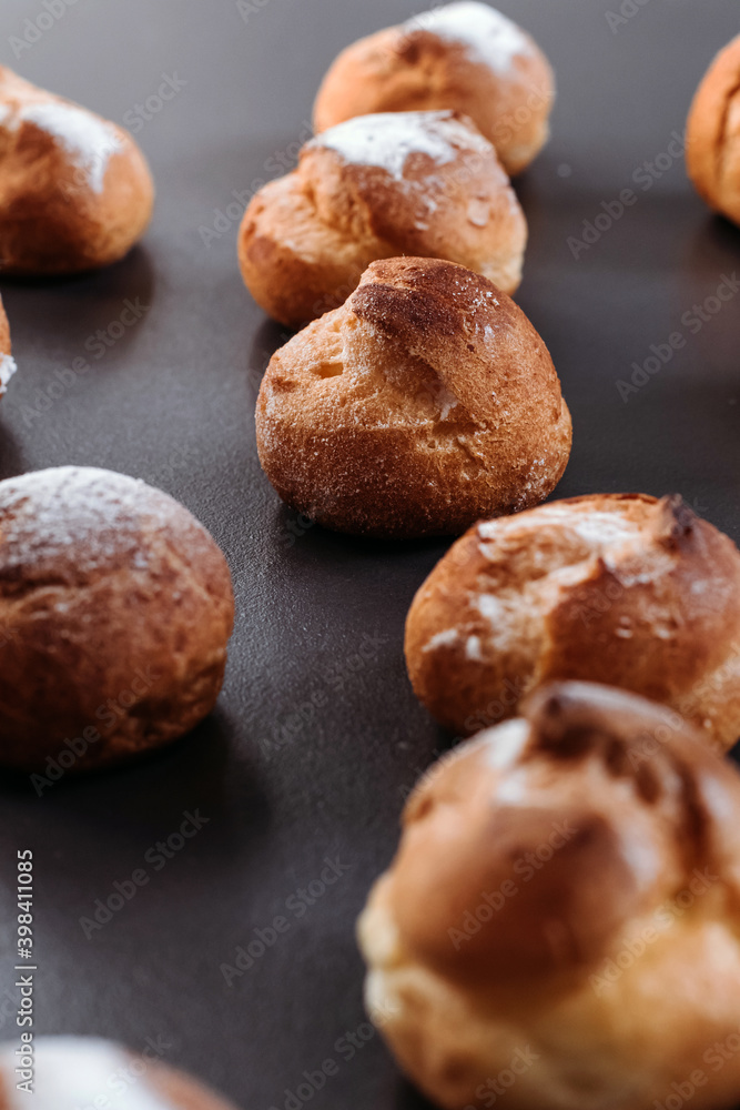 French profiteroles with cream. Many sweets on dark background.