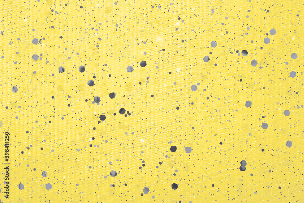 Illuminating yellow background with Ultimate Gray glitter confetti. Color of the year 2021