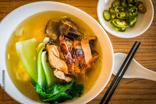 a bowl of chinese wanton noodle soup with chicken char siew and vegeatable on top photo