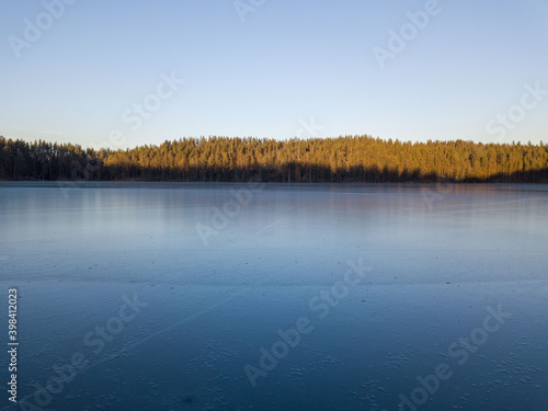 Thin transparent ice on the surface of a forest lake in Karelia, northwest of Russia
