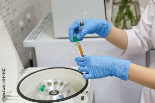 extraction of plasma from blood. blood test in the laboratory. doctor's hand holding a vacuum test tube with blood against centrifuge. © Петр Смагин