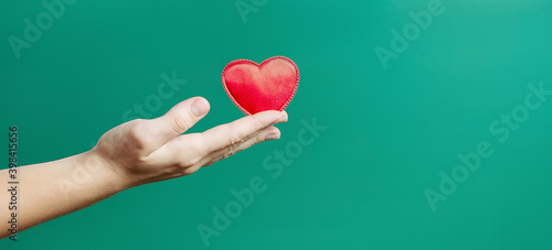 Hand holding red heart with copy space.Concept of Love and Health care,family insurance.World heart day, health day.Valentine's day. green background.