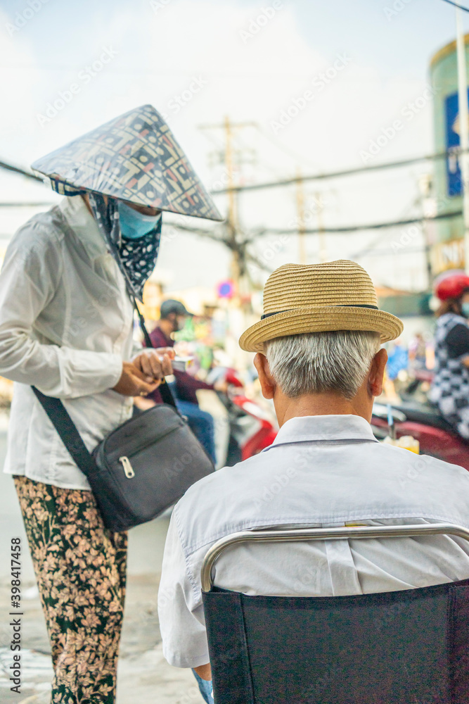 a scene of a woman in a conical hat selling a lottery ticket to an elderly man in Vietnam a scene of a woman in a conical hat selling a lottery ticket to an elderly man in Vietnam